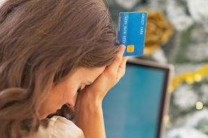 クレジットカードを持ちながらへこむ女性