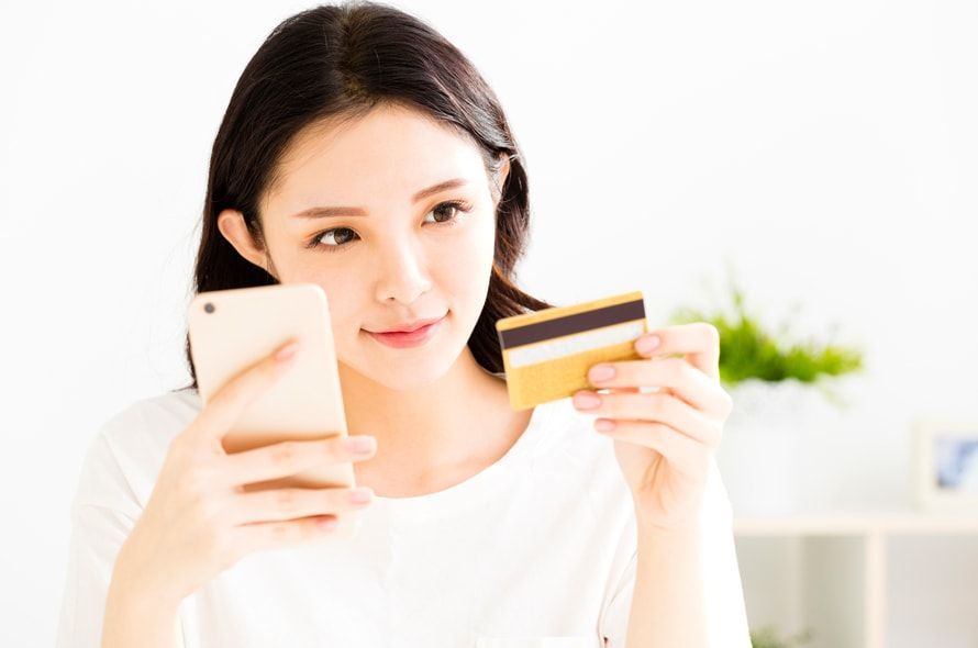 スマホを見ながらカードを持つ女性