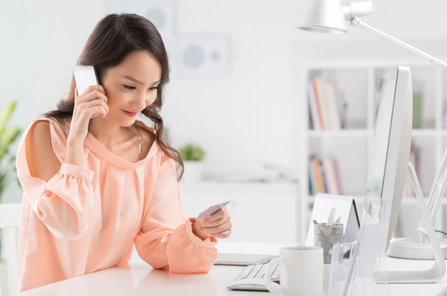 電話をかけながらカードを見る女性