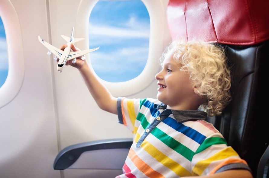 機内で飛行機の模型を飛ばして遊ぶ男の子