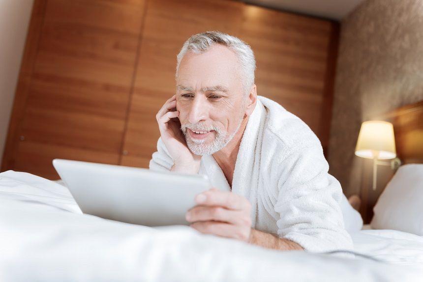 ベッドの上でノートパソコンを確認する男性