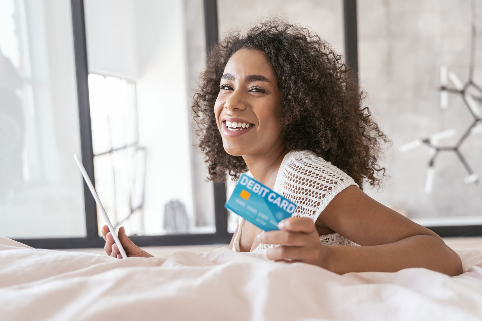デビットカードを持ち微笑む白い服を着た女性